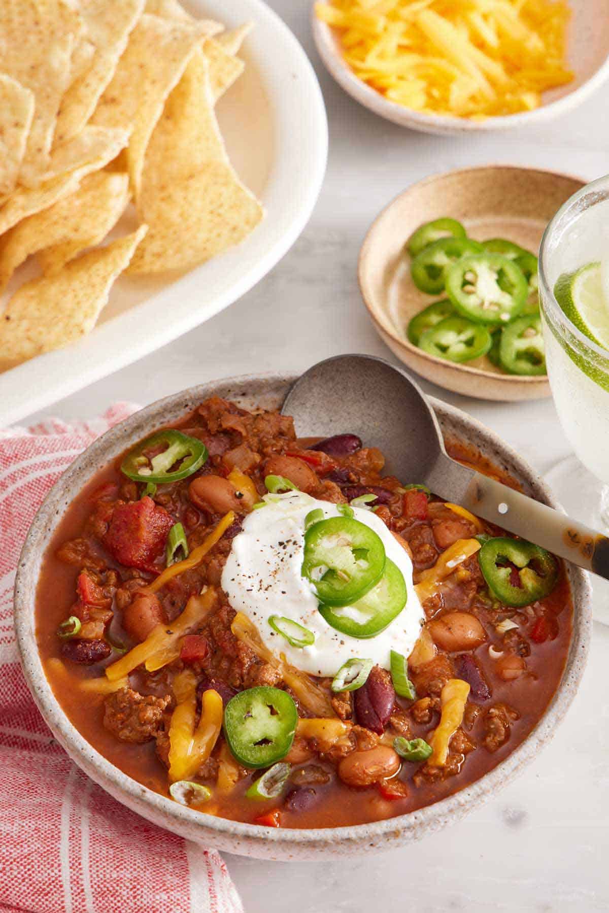 A bowl of chili with various toppings like sour cream, cheese, and jalapeños.