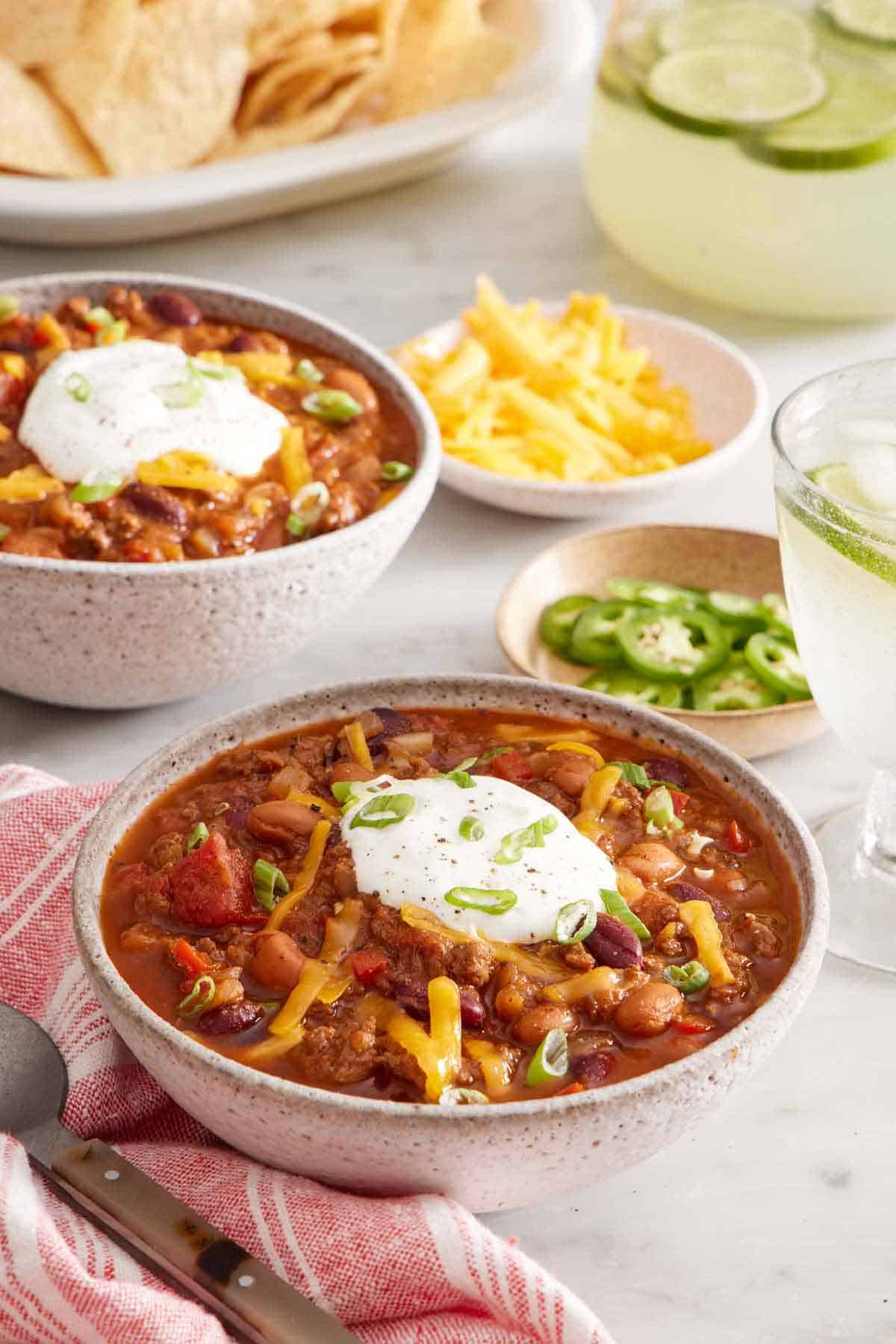 A bowl of chili topped with sour cream, shredded cheese, and green onions.