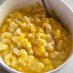 A white bowl with homemade mac and cheese in it and a spoon.