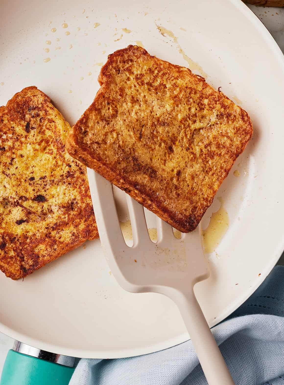 Flipping a golden-brown slice of French toast in a skillet