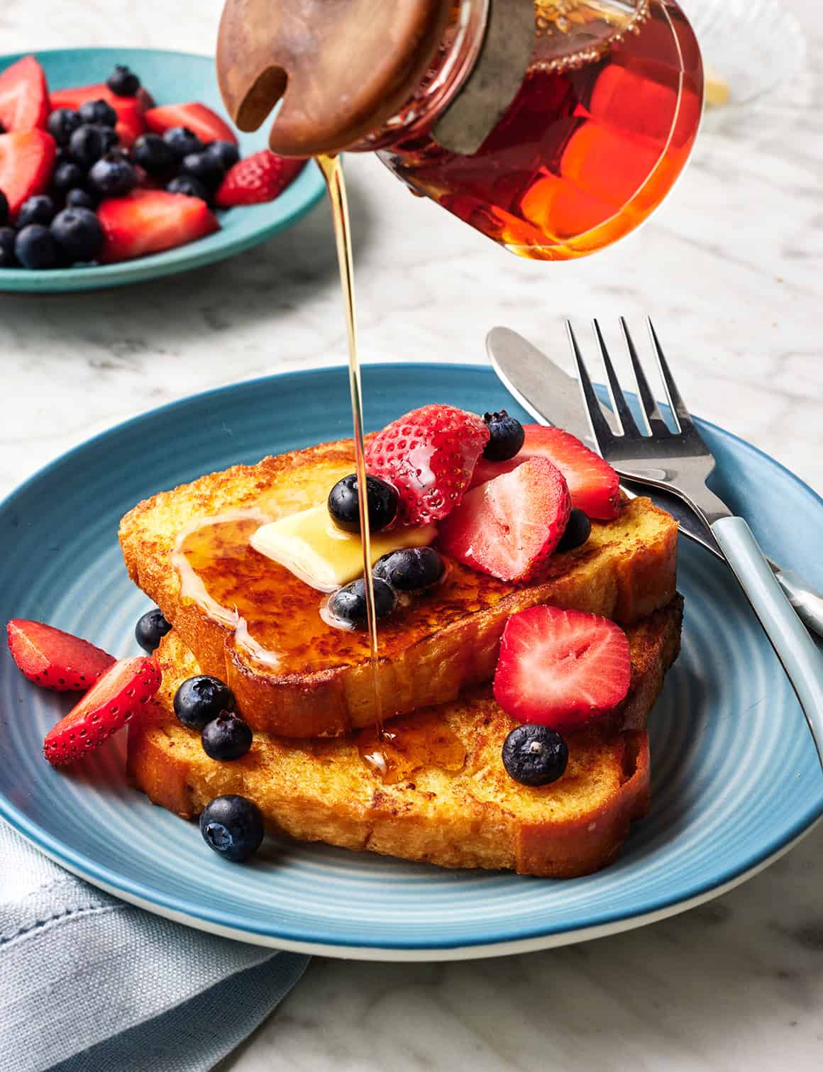 A beautiful plate of French toast topped with berries and maple syrup